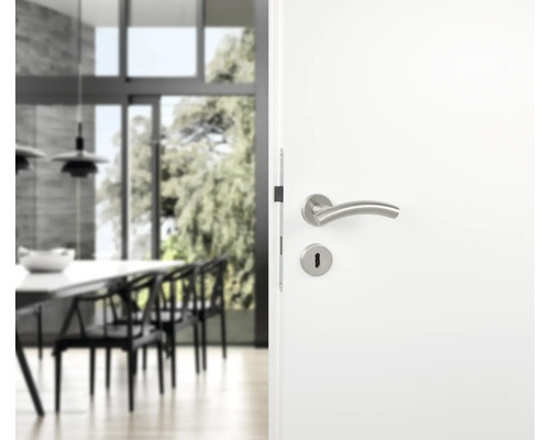 Weiße Tür mit Edelstahl-Drückergarnitur vor hellem Wohnbereich