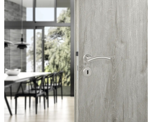 Holztür mit silberfarbenem Türgriff in einem hellen Raum