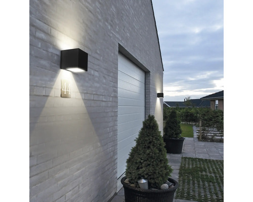 Außenansicht eines Hauses mit Garagentor und quadratischen Wandleuchten