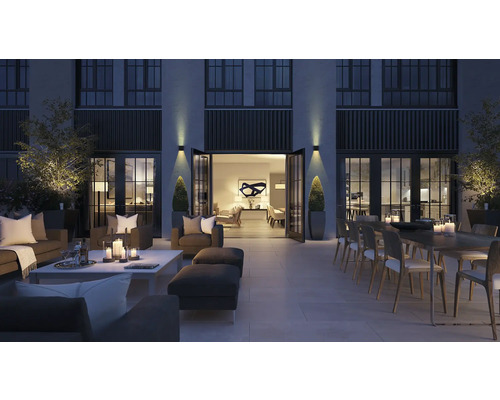 Große Terrasse mit Sitzmöbeln, Esstisch und Dekoration bei Nacht.