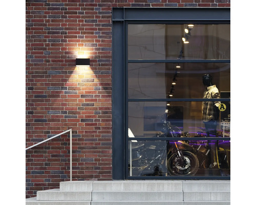 Außenansicht eines Geschäfts mit Ziegelwand und beleuchteter Außenleuchte
