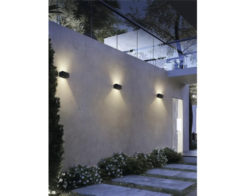 Moderne Außenwand mit drei schwarzen Leuchten, die die Wand beleuchten.