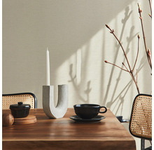 Beigefarbene Wand mit Dekor auf einem Esstisch mit einer Kerze, einer Teetasse und einer kleinen Schüssel