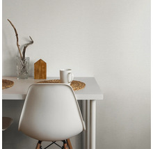 Nahaufnahme eines Tisches mit Dekorationsgegenständen und einer weißen Wandtapete mit Textur