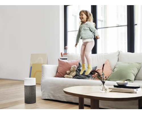 "Ein Mädchen springt auf einem Sofa in einem hellen Wohnzimmer