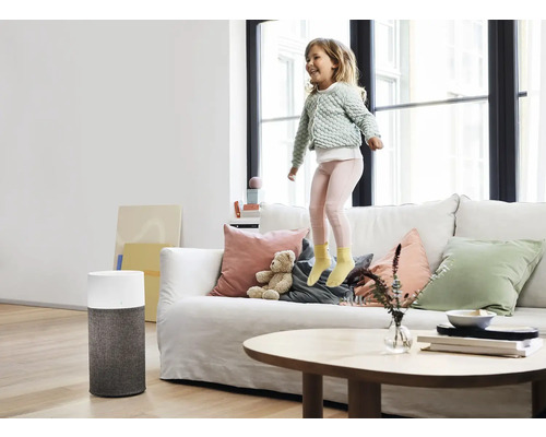 Raumszene mit Luftreiniger und Kind, das auf einem Sofa springt, für saubere Luft im Wohnraum