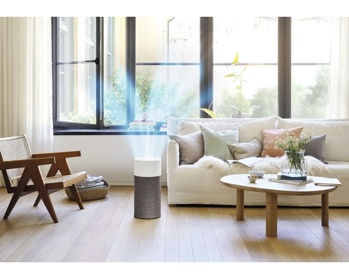 Luftreiniger in einem hellen Wohnzimmer mit Sofa und Holzmöbeln.