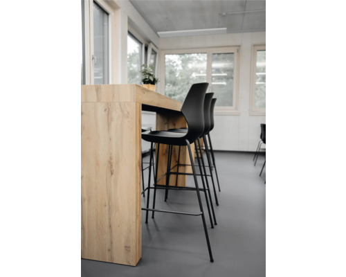 Szene mit Stehtisch und schwarzen Barhockern in einem hellen Raum.