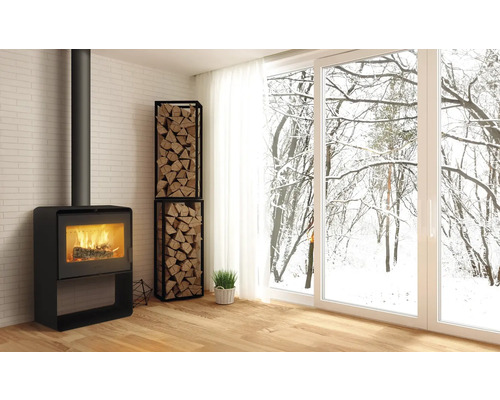 Wohnzimmer mit Kaminofen, Holzregal und Blick auf verschneite Bäume