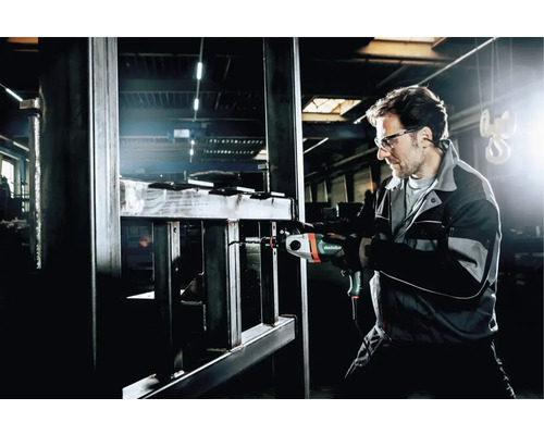 Ein Mann mit Schutzbrille bohrt mit einer Metabo Bohrmaschine in Metall.