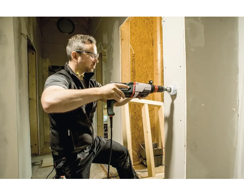 Handwerker bohrt Loch in eine Wand mit einer Bohrmaschine von Metabo