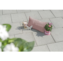 Dekorative Gartenszene mit Pflastersteinen, Kissen, Kerze, Schmetterling und Topfpflanze