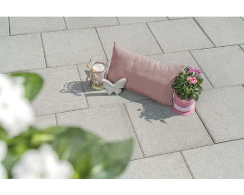 Dekorative Gartenszene mit Pflastersteinen, Kissen, Kerze, Schmetterling und Topfpflanze
