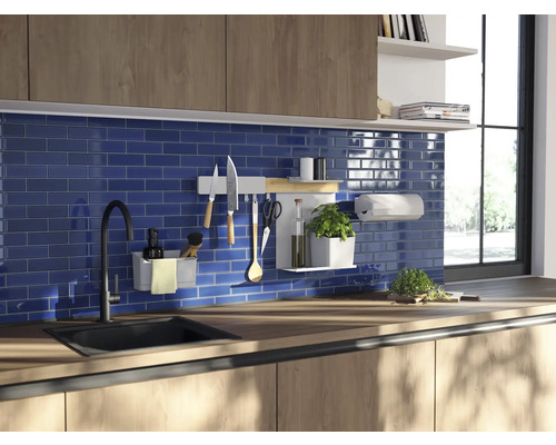 Küchenszene mit Spüle, Armatur, Arbeitsplatte und verschiedenen Küchenutensilien an einer Wandhalterung