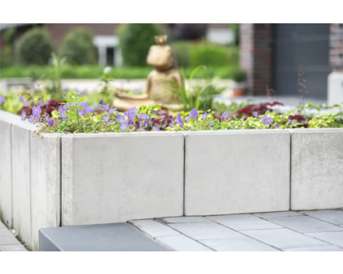 Hochbeet aus Betonsteinen mit Blumen bepflanzt im Garten.