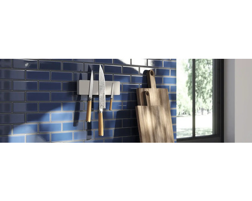 Küchenszene mit blauen Fliesen, magnetischem Messerhalter mit Messern und Holzschneidebrettern