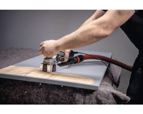 Eine Person benutzt eine Mauernutfräse auf einem Werkstück.