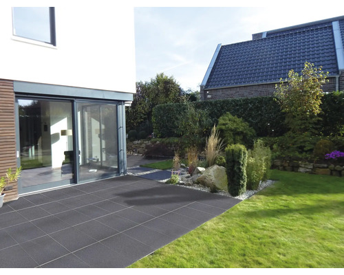 Garten mit Terrasse aus Steinplatten, angrenzend an ein modernes Wohnhaus