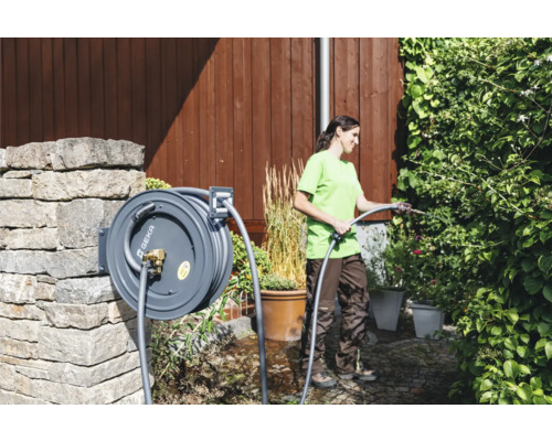 Frau gießt Pflanzen mit einer Schlauchtrommel von Geka im Garten
