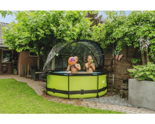 Zwei Kinder spielen in einem grünen rundem Planschbecken mit Überdachung im Garten.