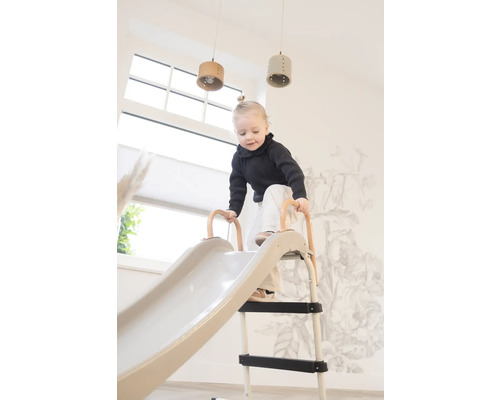 Kleinkind klettert auf eine Kinderrutsche im Innenbereich.