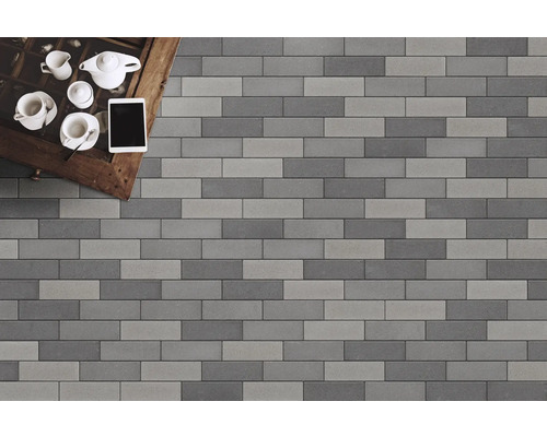 Verlegung von Pflasterklinkern in Grau- und Anthrazittönen mit Teegeschirr und Tablet