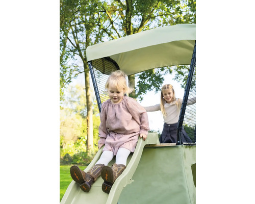 Mädchen rutscht auf Spielplatzrutsche im Garten.