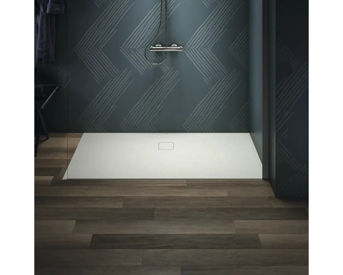 Ebenerdige Dusche mit Duscharmatur vor gemusterter Wand