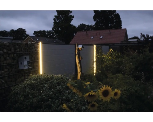 Gartenansicht mit Gabionenzaun, Holzzaun und dekorativer LED-Beleuchtung