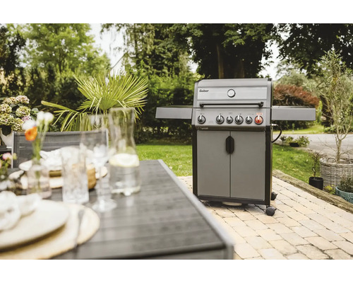Gasgrill im Garten mit Tisch und Pflanzen