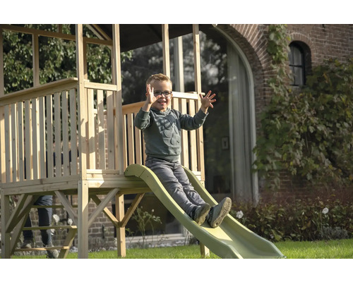 Junge rutscht auf einer Holzspielturm-Rutsche im Garten.