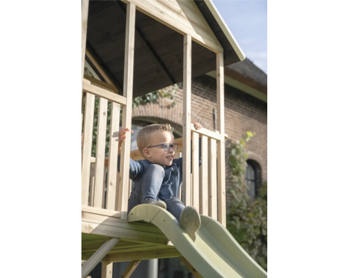 Junge auf Holzspielturm mit Rutsche im Garten