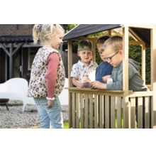 Kinder spielen in einem Holzspielhaus im Garten.