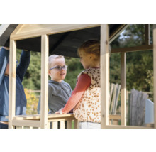 Zwei Kinder spielen in einem unbehandelten Holzspielhaus im Garten.