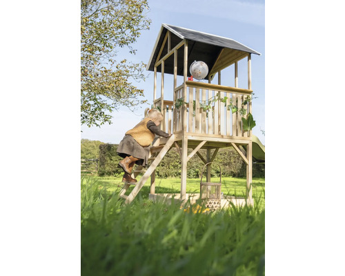 Kind klettert auf ein hölzernes Spielhaus mit Rutsche im Garten