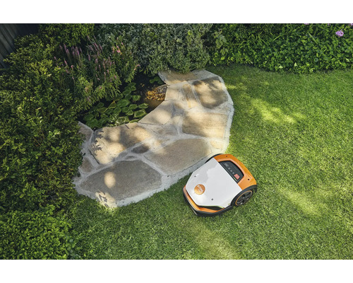 Szene mit einem Rasenmäherroboter auf einem Rasen neben einem Steingarten mit Teich