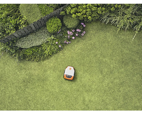 Ansicht von oben auf einen Rasenmähroboter auf einem Rasen neben einem Garten