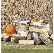 Akkukettensäge mit Arbeitsschutzhelm, Schutzbrille und Handschuhen auf Holzstapel
