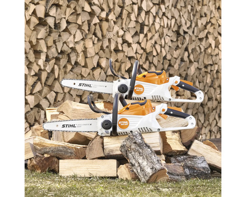 Zwei Akku-Kettensägen von Stihl auf einem Stapel Holz