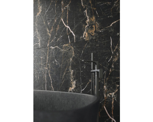 Badezimmerwand mit Fliesen in Marmoroptik, kombiniert mit einer freistehenden Badewanne und Armatur