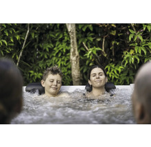 Entspannte Familie genießt ein warmes Sprudelbad im Garten