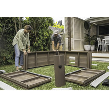 Zwei Personen montieren ein Gartenhaus auf einer Rasenfläche.