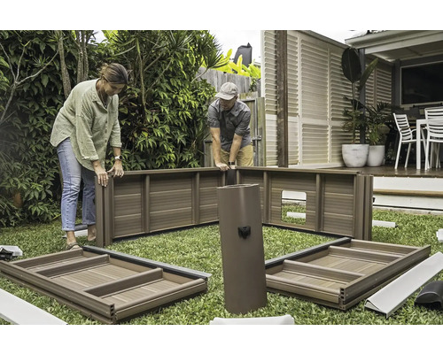 Zwei Personen montieren ein Gartenhaus auf einer Rasenfläche.