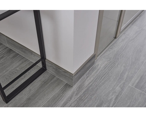 Detailaufnahme von Laminatboden mit grauer Holzoptik und Fußleisten