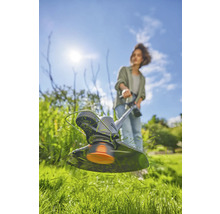 Frau arbeitet mit einem Rasentrimmer im Garten.