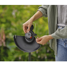 Eine Person wechselt die Spule eines Rasentrimmers aus.