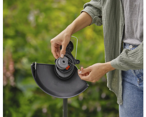 Eine Person wechselt die Spule eines Rasentrimmers aus.