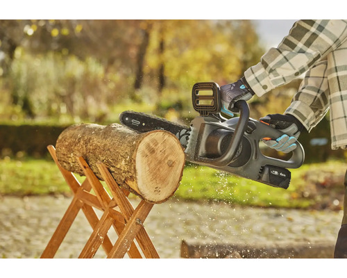 Akku Kettensäge beim Sägen eines Holzscheits auf einem Holzbock