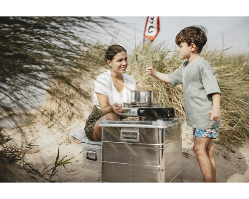 Frau und Kind kochen im Freien mit einem Campingkocher und einem Aluminium Campingküchenschrank.