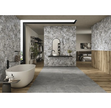 Modernes Badezimmer mit freistehender Badewanne, Waschbecken und Fliesen in Steinoptik für ein helles und geräumiges Ambiente.